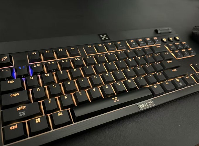 A close-up angled shot of a black gaming keyboard with orange backlighting, featuring keys like ctrl, shift, alt, and spacebar.