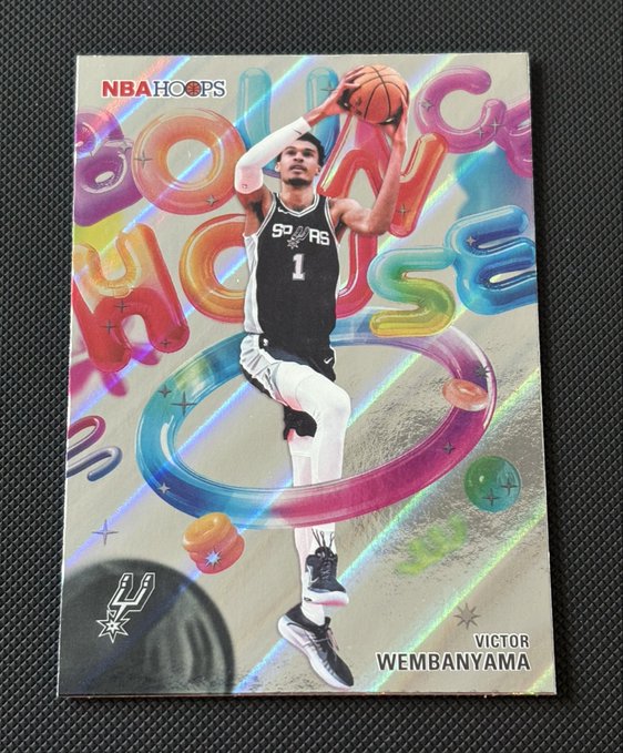 A holographic NBA Hoops trading card featuring Victor Wembanyama of the San Antonio Spurs in a black jersey (number 1), shown mid-jump with a basketball.