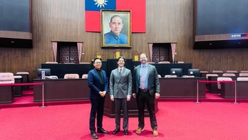 The image shows a group of four men standing together, posing for a photo in front of a large painting or portrait that features an Asian man's face. The men appear to be dressed formally, with one wearing a suit and tie, another in a gray suit, and two others in suits as well. They are all smiling at the camera, creating a sense of camaraderie among them.

The backdrop for this group photo is a red carpeted room, which adds a touch of elegance to the scene. The painting or portrait on display seems to be of interest to some central banks, as indicated by the text in the image that reads "Some central banks are interested in Bitcoin." This suggests that these men might be involved in discussions or decisions related to cryptocurrency and its impact on traditional financial systems.