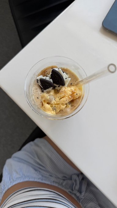 A frappuccino topped with Oreo cookies in a plastic cup sits on a white café table, paired with a casual weekend check-in about ignoring onlookers and wishing followers a great weekend.