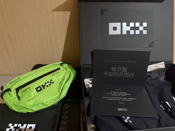An OKX promotional gift box for the Mid-Autumn Festival with Chinese text '等月圆 不如向月而行', containing a neon green OKX fanny pack and black merchandise.