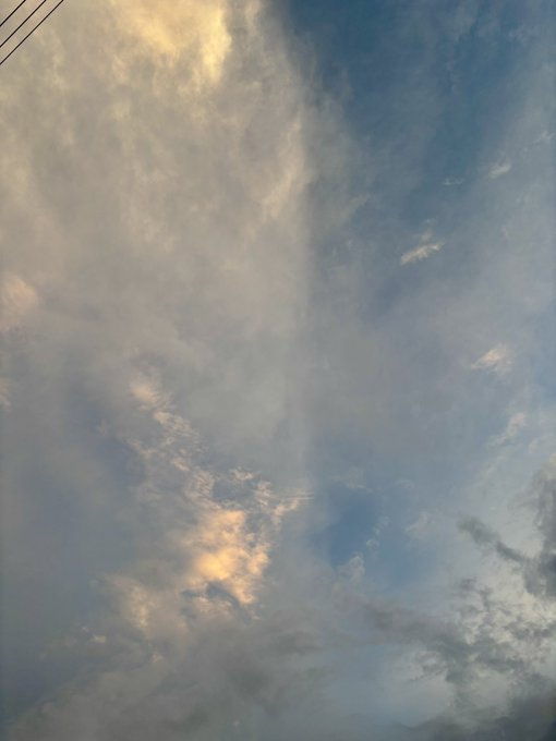 A serene sky filled with soft, billowing clouds bathed in warm golden and cool blue hues, with faint power lines visible in the upper left corner. The peaceful twilight atmosphere perfectly complements the inviting suggestion to enjoy a refreshing evening walk.