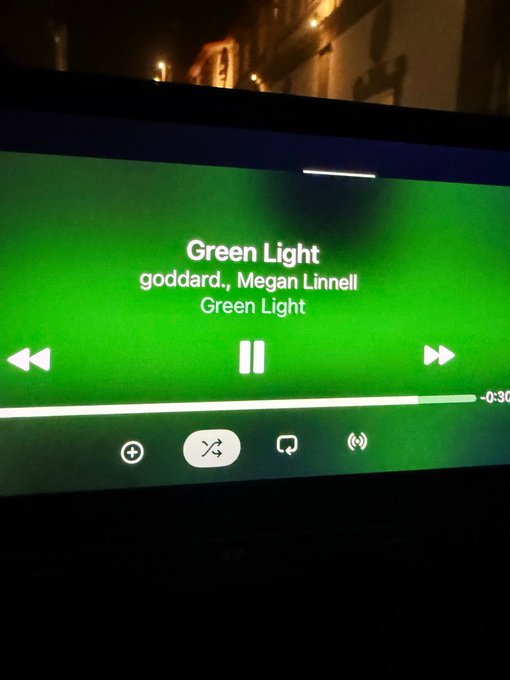 A smartphone screen displays Spotify playing the song "Green Light" by goddard. and Megan Linnell at -0:30, seemingly posted in reference to the "$XRP" cryptocurrency ticker.