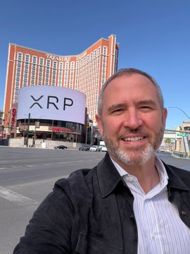 A man takes a selfie in front of The Resorts World Las Vegas hotel, which has a large banner displaying "XRP" — the digital asset associated with Ripple, the company whose CEO Brad Garlinghouse recently revealed the firm nearly shut down following its SEC lawsuit.
