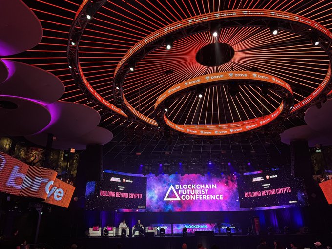 Interior of a large venue featuring a striking circular ceiling installation with 'brave' branding, hosting the 'Blockchain Futurist Conference - Building Beyond Crypto.'