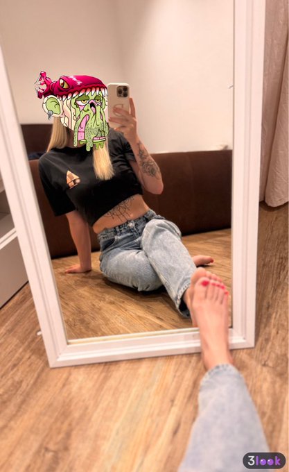 A mirror selfie shows a person wearing a cartoon pickle filter over their face, dressed in a black crop top and baggy jeans.