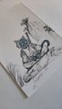A piece of paper bearing a blue and black drawing of a stylized, fierce-looking creature with spiky features.