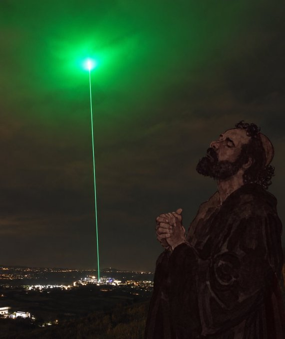 A statue of a bearded figure with clasped hands in prayer poses next to a bright green laser beam shooting into the night sky above a distant cityscape, visually tying to the post's branding of "defipriest" with the green beacon serving as a metaphor for the crypto signals being "prayed" upon.