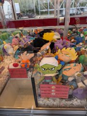 A wider view of the same claw machine from image 1, showing more Dragon Ball plush toys including Super Saiyan Goku and other characters piled inside.