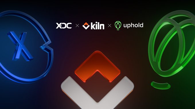 A promotional graphic announcing "$XDC staking is now live on Uphold," featuring the XDC logo in blue alongside the green Uphold emblem, with the Kiln logo and a larger Kiln 3D emblem centered against a dark background.