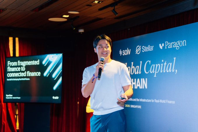 A man speaks into a microphone at a conference, with a presentation slide behind him reading 'From fragmented finance to connected finance' by Apoorv, and sponsor logos for Solv, Stellar, and Paragon visible.