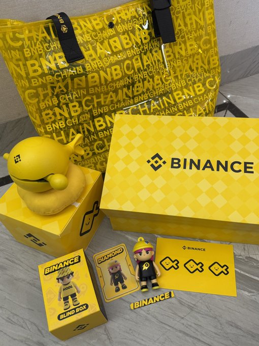 The image features a collection of items, including a yellow toy duck, a yellow box with "Binance" written on it, and other small figurines or toys. The objects are arranged on a table, creating an interesting display that captures attention. The presence of these items in the image suggests that they might be related to the post about Bitcoin or cryptocurrency, as the word "Binance" is visible among them.