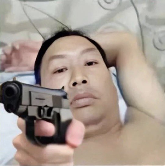 A close-up selfie-style photo of a man pointing a silver handgun directly at the camera.