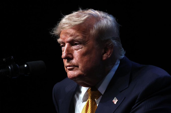 The image captures an official-looking individual, presumably President Trump, during a serious engagement, possibly a meeting or a press conference, considering the formal attire and the presence of a microphone, which aligns with the context provided by the accompanying post. The post mentions a meeting to discuss the Crypto Clarity Act, a significant step towards regulating the cryptocurrency framework in the United States, and Trump's involvement suggests his role in shaping this regulatory environment.
