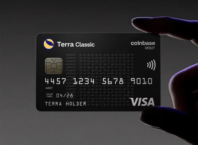 The image shows a person holding up a black credit card with the Visa logo, which has the number "4537" printed on it. The text "Terra Classic" is also visible on the card. The background of the image is dark gray, making the credit card stand out prominently. The post suggests that you can buy anything using Terra Vault, and the person holding up the card is likely promoting this service or product.