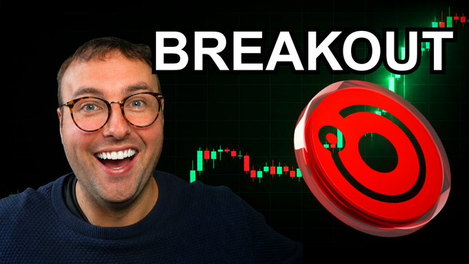 In this image, a man wearing glasses and a blue sweater is shown smiling next to a computer screen that displays Bitcoin prices. There are green and red candlesticks visible across multiple levels of the chart, showing an upward trend in Bitcoin value over time. The text above the chart indicates that there will be a breakout soon, possibly due to an upcoming event or news release related to Bitcoin.