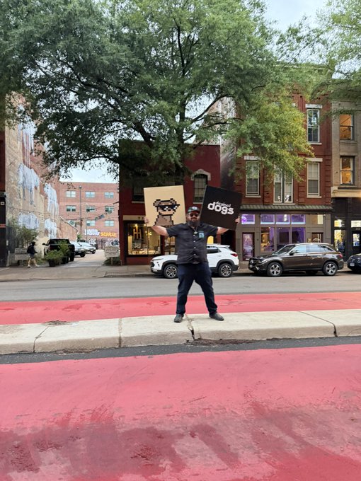 iced coffee shop with a red roof, black and white sign reading "DOGS", and a tree-lined street with parked cars.