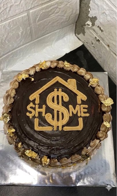 In this image, there's a chocolate cake on top of a silver cake stand placed against a white wall. The cake has a unique design featuring a house-shaped border around its edges. Above the cake, there are gold foil decorations that say "SHH". Below it, there is a caption that says "After chasing every shiny new meta I finally found $HOME No promises No gimmicks No endless buzzwords Just a place where the community shows up builds together and stays HOME isn't where the pump starts HOME is where you stay when the noise ends.". The combination of elements within this image creates an interesting visual theme that may appeal to those who enjoy home-related decorations or have an interest in real estate.