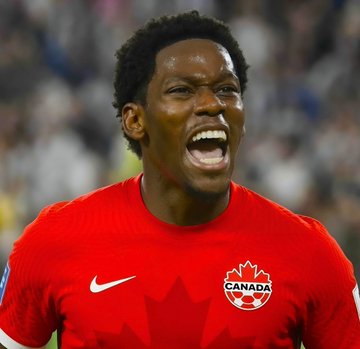 A player wearing a red Canada national team jersey, featuring the maple leaf crest, Nike logo, and "CANADA" text, celebrates passionately with an open-mouthed shout in front of a stadium crowd. The image aligns with the post about a $1.2M bet on Canada to win against South Africa, capturing the intense emotion of Canadian soccer fans backing their team.