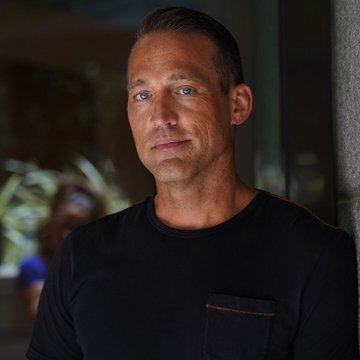 A confident-looking man in a black t-shirt stands against a softly lit background, projecting a calm yet assertive demeanor that reinforces the post's optimistic message of "More tides are turning. Bullish!" His steady gaze and composed expression visually echo the sentiment of a positive market shift.
