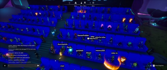 A screenshot from a virtual concert venue showing numerous glowing avatar spectators with usernames like 'GanonFodder,' 'Queefcheetah,' and 'Zards' visible above their heads in a dimly lit stadium.