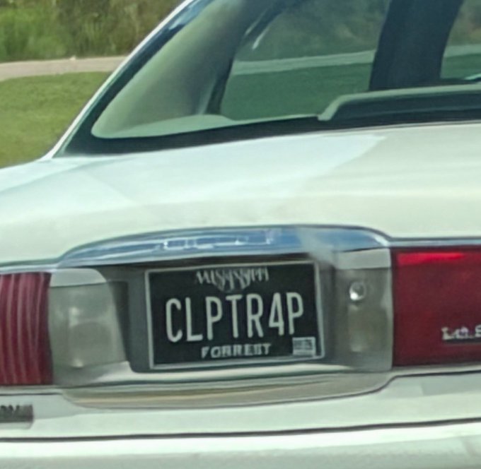 The rear of a white car with a custom 'CLPTR4P' license plate reading 'FORREIT', appearing to read as 'CLIPTRAP FORFEIT' when reflected in a mirror.