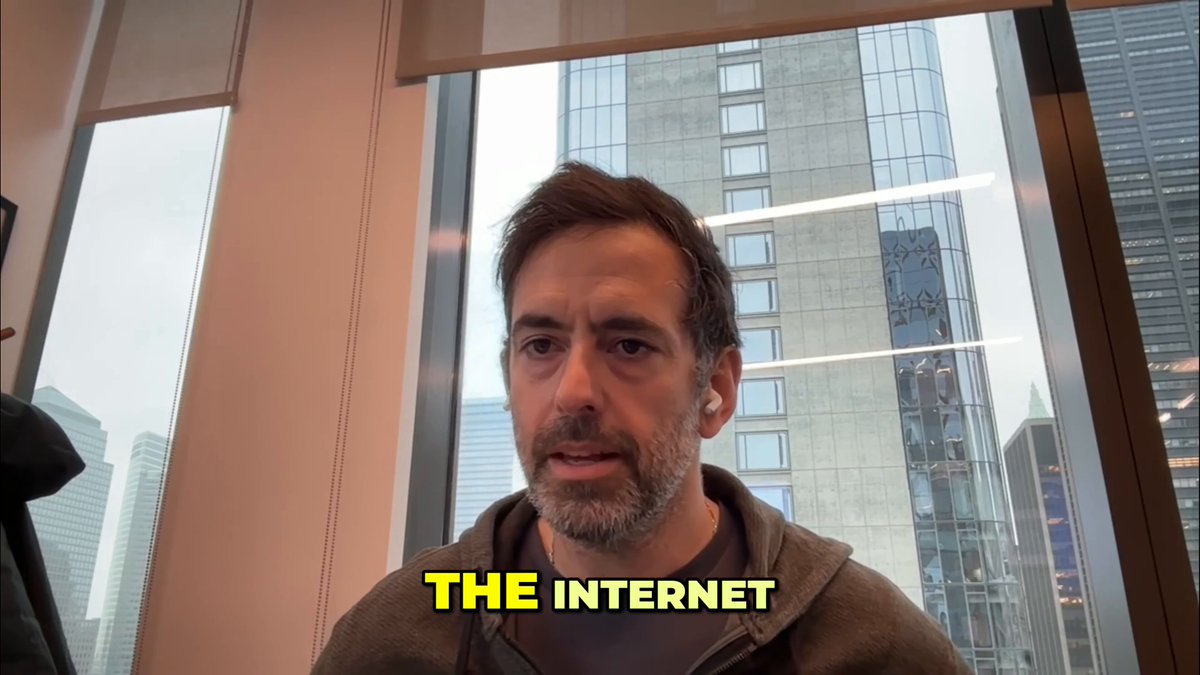 The image features a man wearing a hoodie, sitting at a desk with his head tilted back as if he's deep in thought or contemplation. The background of the image shows a window overlooking a cityscape, providing an urban setting for the scene. There is also text on the image that reads "THE INTERNET" and "Franklin Templeton's BENJI on stellar.org/blog/ecosystem". This suggests that the man might be discussing or contemplating the concept of natively tokenizing on a public chain, which is an important aspect of blockchain technology.