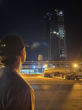 A man in a cap watches a rocket on a launch pad at night, with the "2024" and "2026" text suggesting the image captures an upcoming or past launch milestone bridging the two years.