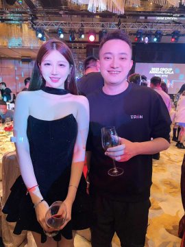 A photo of a man and woman posing together at what appears to be a formal event or gala, both holding wine glasses.