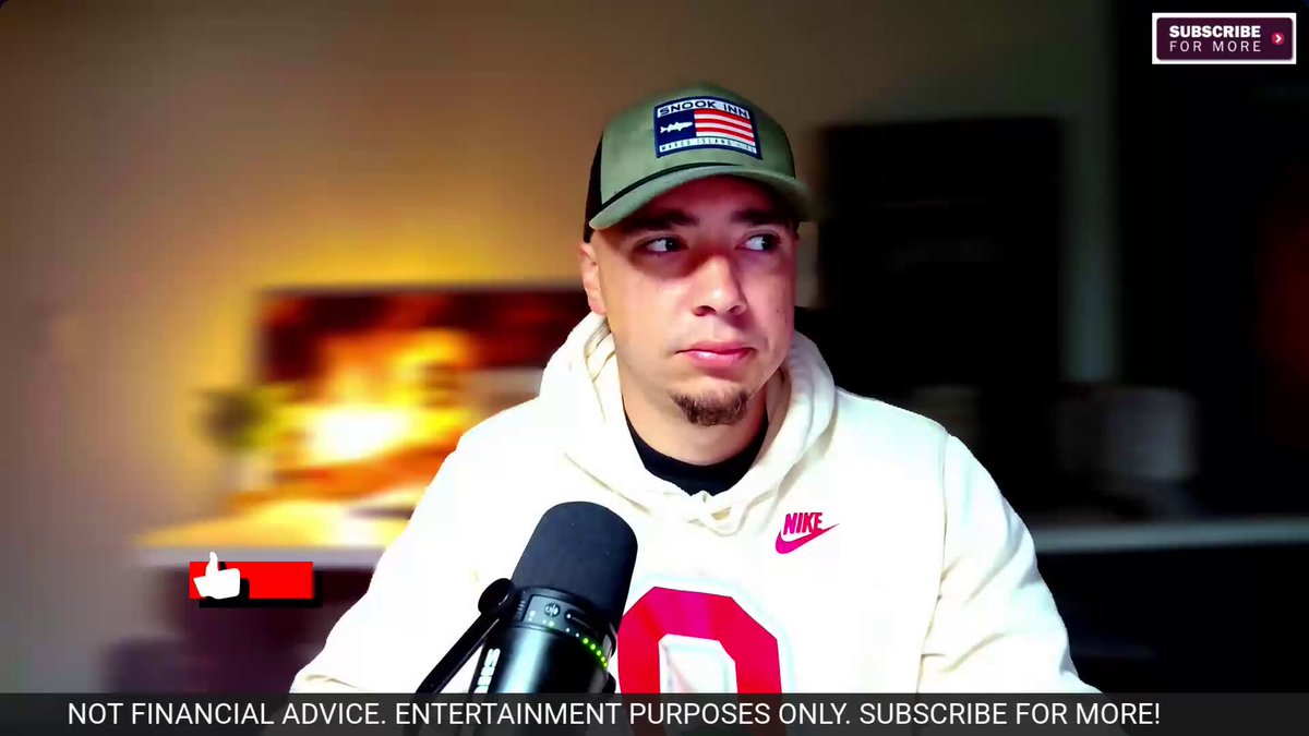 The image shows a man wearing a white sweatshirt with an American flag design, sitting at a desk with a microphone in front of him. He appears to be giving advice or talking about something related to cryptocurrency. The background features a TV screen displaying news articles, including one that says "Trump drops news for crypto and $XRP and Ripple CEO Brad Garlinghouse speaks out on it".