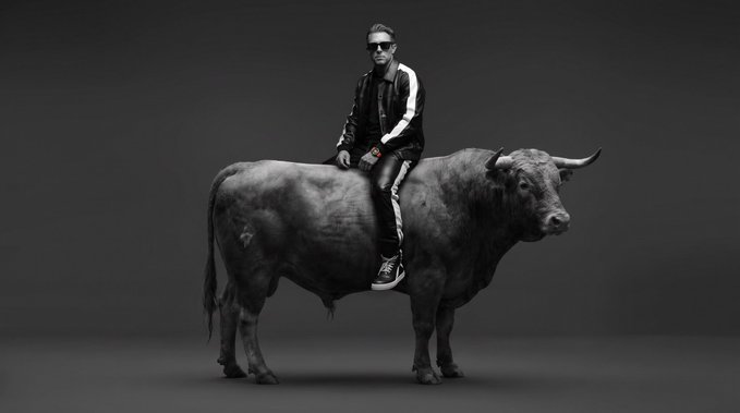 A black-and-white image shows a man in a leather jacket and sunglasses riding atop a large bull, visually symbolizing the "bullish" sentiment expressed in the accompanying post urging investors to send $TBB toward a $45M market cap.