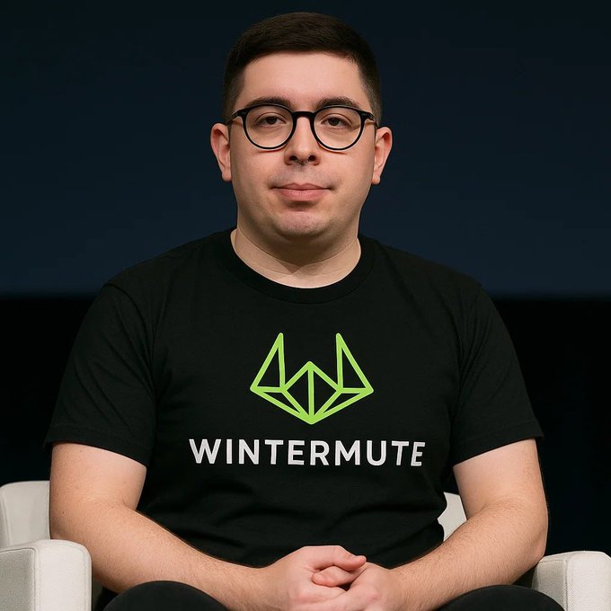 A portrait of a man with glasses wearing a black t-shirt with a green logo and the word 'WINTERMUTE' printed on it, sitting against a dark background.