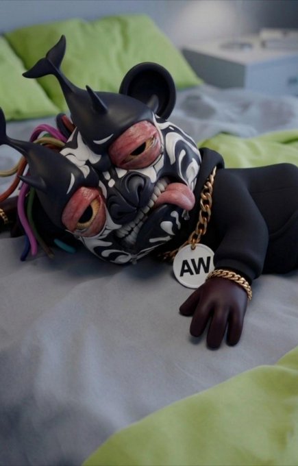 A designer toy or art figure of a character with a stylized black and white masked face, horns, a gold chain with an 'AW' pendant, and colorful dreadlock-like accents.