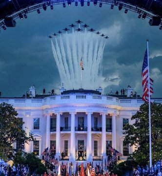 The White House is illuminated at twilight as the U.S. Air Force Thunderbirds perform a flyover, leaving white contrails against the dark blue sky, with an American flag flying on the right.