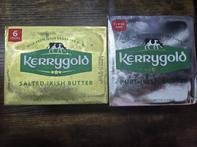 Two boxes of Kerrygold butter on a wooden surface: a yellow box of Salted Irish Butter (6 sticks) on the left and a silver box of Pure Irish Butter (3 x 8 oz bars) on the right.