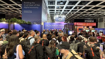 A crowded conference hall with attendees gathered near a stage, where banners read 'Building the trust layer of the digital economy' (HEDERA.COM) and 'STAGE 6'.
