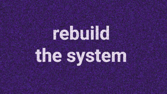 The image features a purple background with white text that reads "Rebuild the system". The text is written in a blocky font, which gives it a more formal appearance. The image also includes an accompanying caption that provides additional information about the content of the image and its relation to the post.