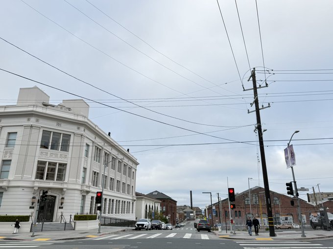 A grey, overcast San Francisco street scene with traffic lights and power lines crisscrossing the sky perfectly captures the city's summer gloom, when a coastal breeze turns an urban intersection into something resembling a blustery voyage along Cape Horn.