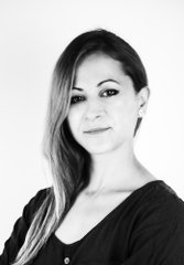 A black and white portrait of a woman with long hair wearing a dark button-up shirt.