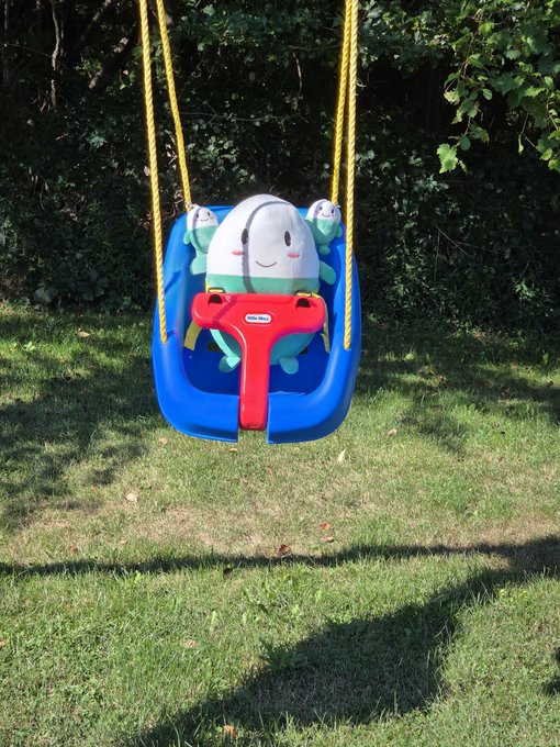 A child's blue bucket swing featuring a smiling whale or jellyfish character with a Little Tikes label sits empty on a grassy yard, waiting for "Cupsey" to hop in for a ride.