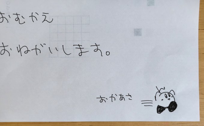 The image shows a piece of paper with handwritten Japanese text on lined grid squares, reading "おむかえ おねがいします。" (which translates to "Please come pick me up"), along with a small drawing of a smiling face and the name "おかあさ" (short for お母さん, meaning "Mom"). The note appears to be a child's simple request for their mother to pick them up, matching the "Today's Note" caption.