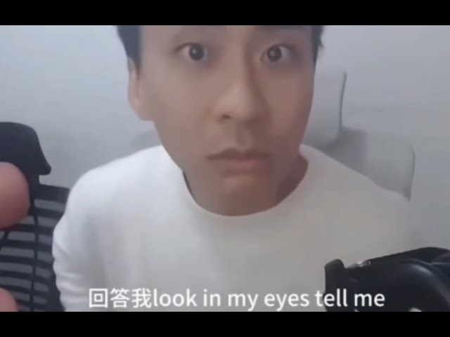 A man in a white shirt stares wide-eyed directly at the camera with an intense, piercing gaze. Chinese and English subtitles at the bottom read "回答我 look in my eyes tell me" (Answer me / Look in my eyes / Tell me).

The image is used as a meme-style reaction that humorously mirrors the post's confrontational tone, with the man demanding a direct, honest answer to whether the author truly believes in the "main storyline" of crypto/financial crime, intensifying the rhetorical question posed in the text.