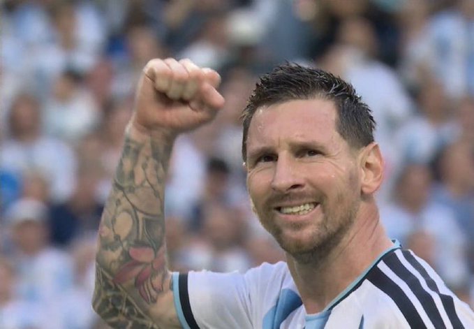 Lionel Messi triumphantly raises his fist with a beaming smile, wearing the iconic Argentina national team jersey, celebrating a goal during the FIFA World Cup. The image perfectly captures the joy and passion referenced in the post about Messi's incredible 7-goal World Cup performance.