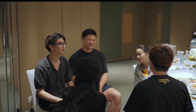 A group of four people, including the man on the right wearing a black shirt with "Toilet Booth w/ Wen Chen" text visible, sit together at a table during what appears to be a casual gathering, likely captured during the 36-hour stay with @heyibinance as mentioned in the post.