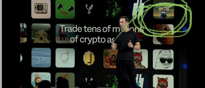 The image features a presentation with several people and screens displaying different crypto tokens, including Bitcoin, Ripple, and Dogecoin. The focal point of the photo appears to be a man who seems to have an intense interest in a potential Base token that is being shown on one of the screens. A notable fact about this particular presentation is the presence of the word "TIBBIR" displayed prominently among the crypto tokens, potentially referring to Bitcoin or another specific crypto coin.