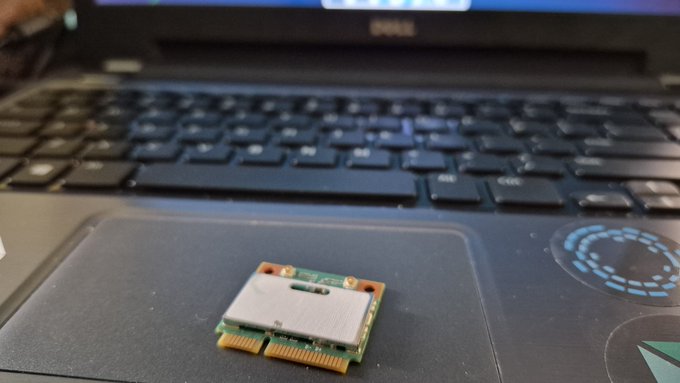 A small removed Wi-Fi card sits on the palmrest of a Dell laptop keyboard, illustrating the "full air gapped" setup described—where the wireless card has been physically extracted from the machine to create an offline crypto wallet environment using Sparrow, Ian Coleman's tools, and a BIP-39 word list.