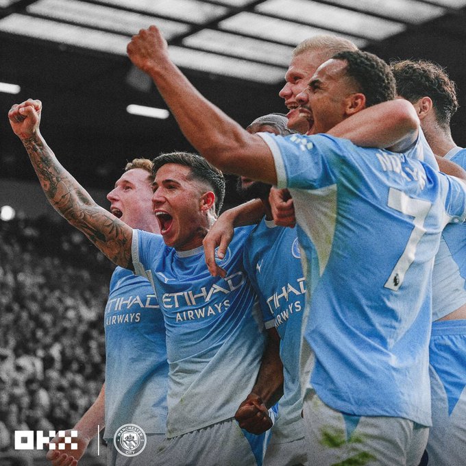Manchester City players in light blue Etihad Airways jerseys celebrate exuberantly, with "OKX" and the Manchester City crest logos visible, capturing the team's triumphant moment that aligns with their perfect start of four straight wins to top the Premier League standings.