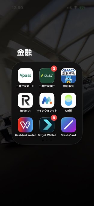 An iPhone home screen displays a Japanese folder titled "金融" (Finance) containing banking and cryptocurrency apps including Vpass, SMBC, GMO, Revolut, My Wallet, Unifi, HashPort Wallet, Bitget Wallet, and Slash Card.