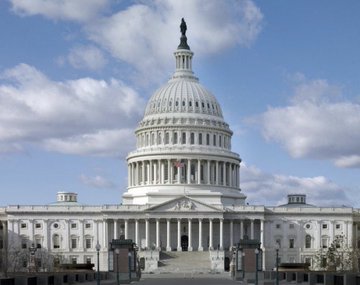 The United States Capitol Building with its white dome and neoclassical architecture photographed against a partly cloudy blue sky.