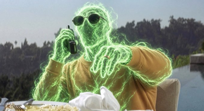 A humorous, edited image of a person wearing a yellow sweater, with their body composed of glowing green energy, holding a walkie-talkie while seated at a table.